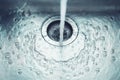 In the sink in the kitchen, water flows from the tap, which flows into the drain hole Royalty Free Stock Photo