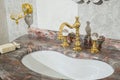 Sink made of expensive marble stone. Vintage design of faucet and taps, in gold and glass handles Royalty Free Stock Photo