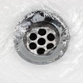 Sink plug drain hole bath plughole, white basin spout, running water macro closeup, stainless steel, china porcelain hand