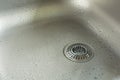 A Sink With Waterdrops And Chrome Drain Strainer