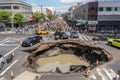 sinkhole in a busy intersection, with cars and people stopped by the sudden collapse