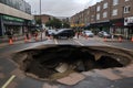 sinkhole opening up in the middle of busy street, with cars driving past