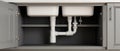 Sinks and plumbing installation under a kitchen counter in a modern home Royalty Free Stock Photo