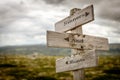 sinners and saints text engraved on old wooden signpost outdoors in nature