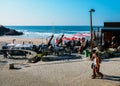 People relax at a cafe overlooking the golden Praia das Macas in Portugal on a sunny winter day