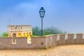 Iron vintage lantern lamp and merlons on tower of Pena Palace castle, green forest in fog, Palacio Nacional da Pena Romanticist