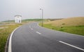 Sinuous asphalted road on grassy acclivity in light winter mist Royalty Free Stock Photo