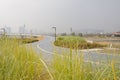 Sinuous road before bridge in light winter mist