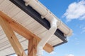 SIP panel house construction. New white rain gutter. Drainage System with Plastic Siding Soffits and Eaves against blue sky. Royalty Free Stock Photo