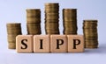 SIPP - acronym on wooden cubes on the background of stacks of coins