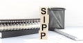 SIPP text on wooden block with notebooks on white background