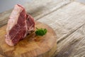 Sirloin chop and corainder leaves on wooden tray against wooden background