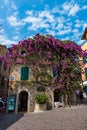 Sirmione, Italy - Aug 22, 2019 - Beautiful ancient house covered with violet flowers in the historical part of the city