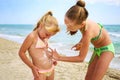 Sister applying protective sunscreen on child