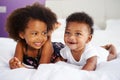 Sister With Baby Brother Lying On Parent's Bed