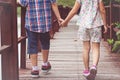 Sister and brother hand in hand walking together in Wood bridge