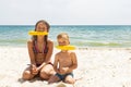 Sister and brother holding corn cobs in their mouth on the sea beach. Summer street eating concept Royalty Free Stock Photo