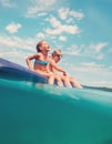 Sister and brother sitting on inflatable mattress and enjoying the sea water, cheerfully laughing when swim in the sea. Careless Royalty Free Stock Photo