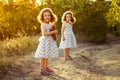 Sister children staying on the road in a park at a walk in the sunshine of the evening sun . Friendship sisters girls. A girl hold