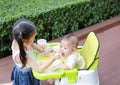 Sister feeding food for her little brother with love on the plastic chair Royalty Free Stock Photo