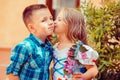 Sister are kissing her Brother on the cheek, warm hugs in nature outside near the house. he looks and smiles happy. Girl shows