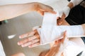 Sister wrapping her brother wrist and arm with bandage around injured hand at home. First aid, accident and injury treatment Royalty Free Stock Photo