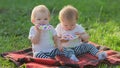 Sisters babies in light clothes sit in park