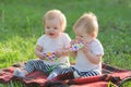 Sisters babies in light clothes sit in the park on grass