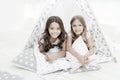 Sisters or best friends spend time together lay in tipi house. Girls having fun tipi house. Girlish leisure. Sisters Royalty Free Stock Photo