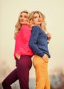 Sisters enjoy colorful outfits on gloomy day sky background. Bright mood. Bright sweaters and pants increase activity