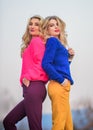 Sisters enjoy colorful outfits on gloomy day sky background. Bright mood. Bright sweaters and pants increase activity Royalty Free Stock Photo