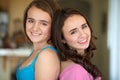 Sisters and friends. Portrait of two young sisters standing back to back smiling a the camera. Royalty Free Stock Photo