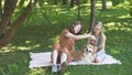 Sisters girls sitting on a park lawn with theirs fluffy corgi dog