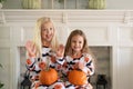 Sisters in Halloween pajamas holding pumpkins Royalty Free Stock Photo