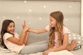 Sisters leisure. Girls in cute pajamas spend time together in bedroom. Sisters communicate while relax in bedroom Royalty Free Stock Photo