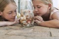 Sisters Looking At Seashells In Bottle