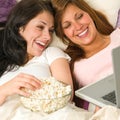 Sisters lying on bed watching funny movie Royalty Free Stock Photo