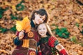 Sisters portrait in forest in fall colors. Beautiful sister standing in a park in autumn. Dreaming girls holding leaves. Royalty Free Stock Photo