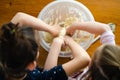 Sisters preparing dough for bread or cake with their hands in a plastic bowl