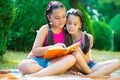 Sisters reading book in summer park