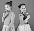 Sisters with round and long shaped lollipops. Children with happy faces pose with candies on green background. Royalty Free Stock Photo