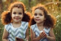 Sisters twin toddlers kissing and laughing in the summer outdoors. Curly cute girls. Friendship in childhood. Warm sunligh Royalty Free Stock Photo