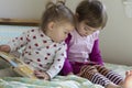 4-year-old girl watching cell phone and 1-year-old girl reading book Royalty Free Stock Photo