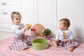 Sisters sit on the floor in the kitchen and play with dry pasta Royalty Free Stock Photo