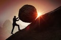 Sisyphus metaphore. Silhouette of businessman pushing heavy stone boulder up on hill