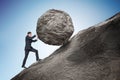 Sisyphus metaphore. Young businessman pushing heavy stone boulder up on hill