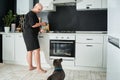 Girl wearing casual clothes instructing her dog to sit while preparing to feed him