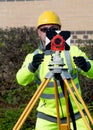 Site engineer assistant setting round prism on tripod pointing it towards total station as instructed