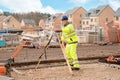 Site engineer in hi-viz installing surveying instrument on construction site