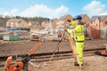 Site engineer in hi-viz installing surveying instrument on construction site